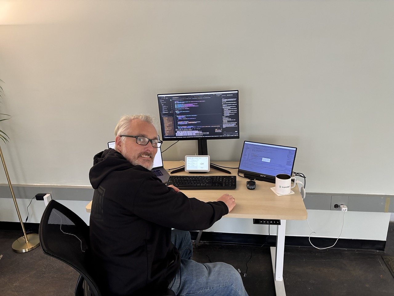 A member coding at a sit-stand desk with an external monitor